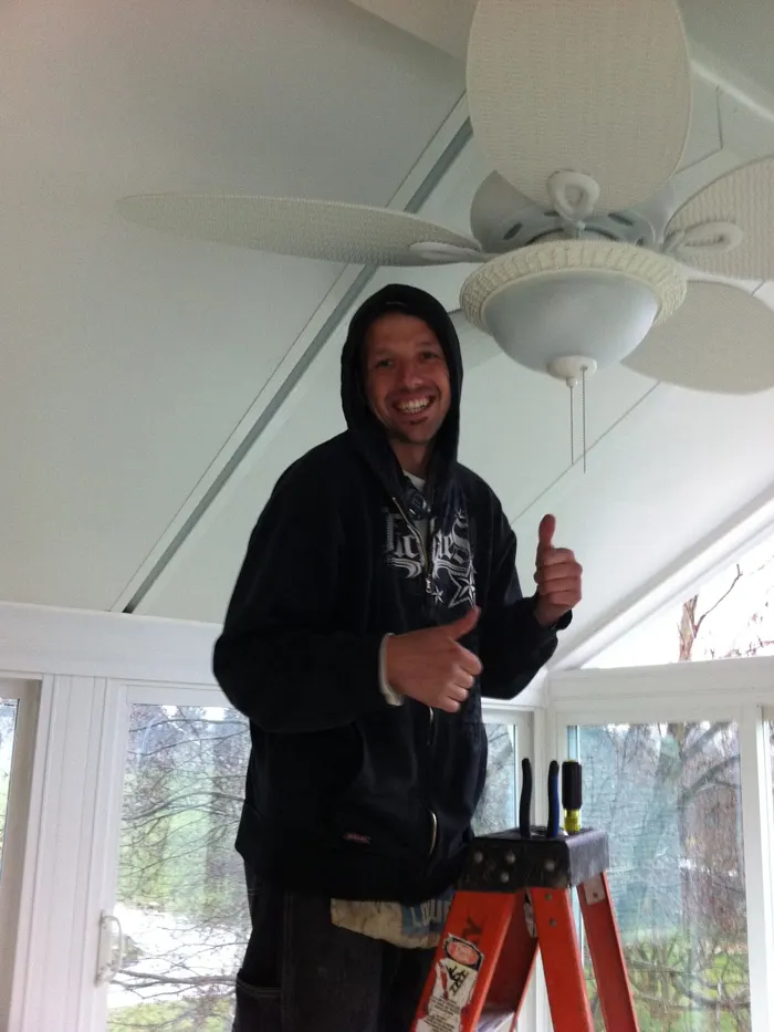 Current Power electrician on a ladder after a porch fan install